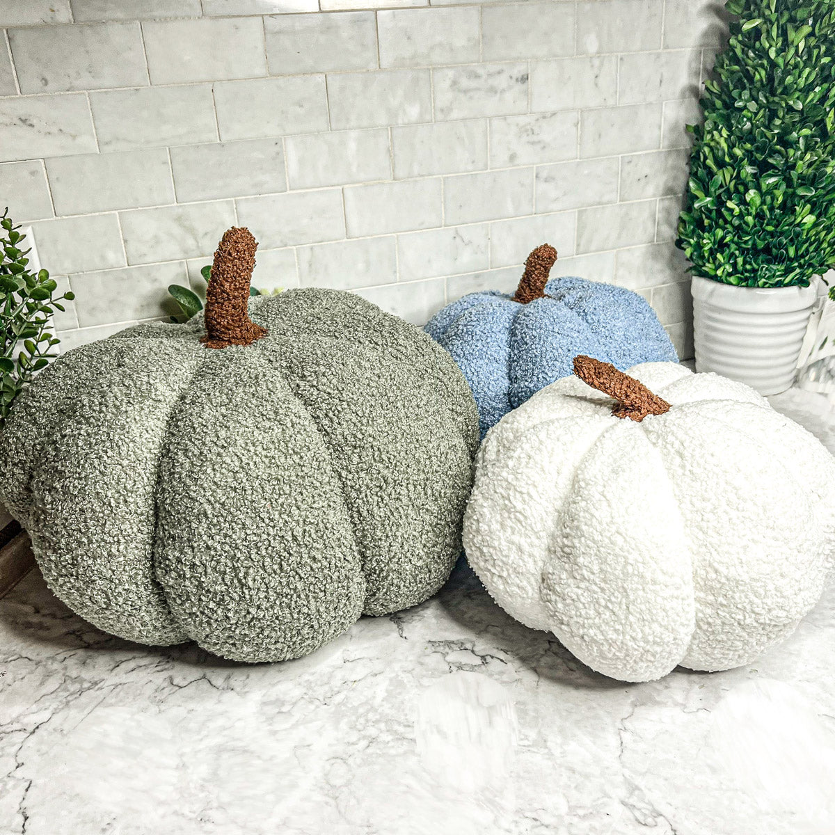 A collection of plush Blair Pumpkins in various colors including blue, gray, and orange, showcasing their soft texture and classic pumpkin shape.