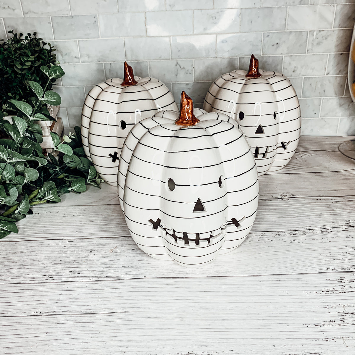 A hand-painted black and white LED pumpkin with a contemporary striped design, perfect for Halloween decor.