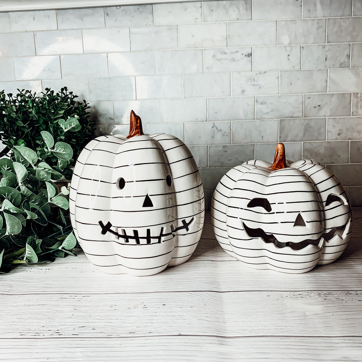 A hand-painted black and white LED pumpkin with a contemporary striped design, perfect for Halloween decor.