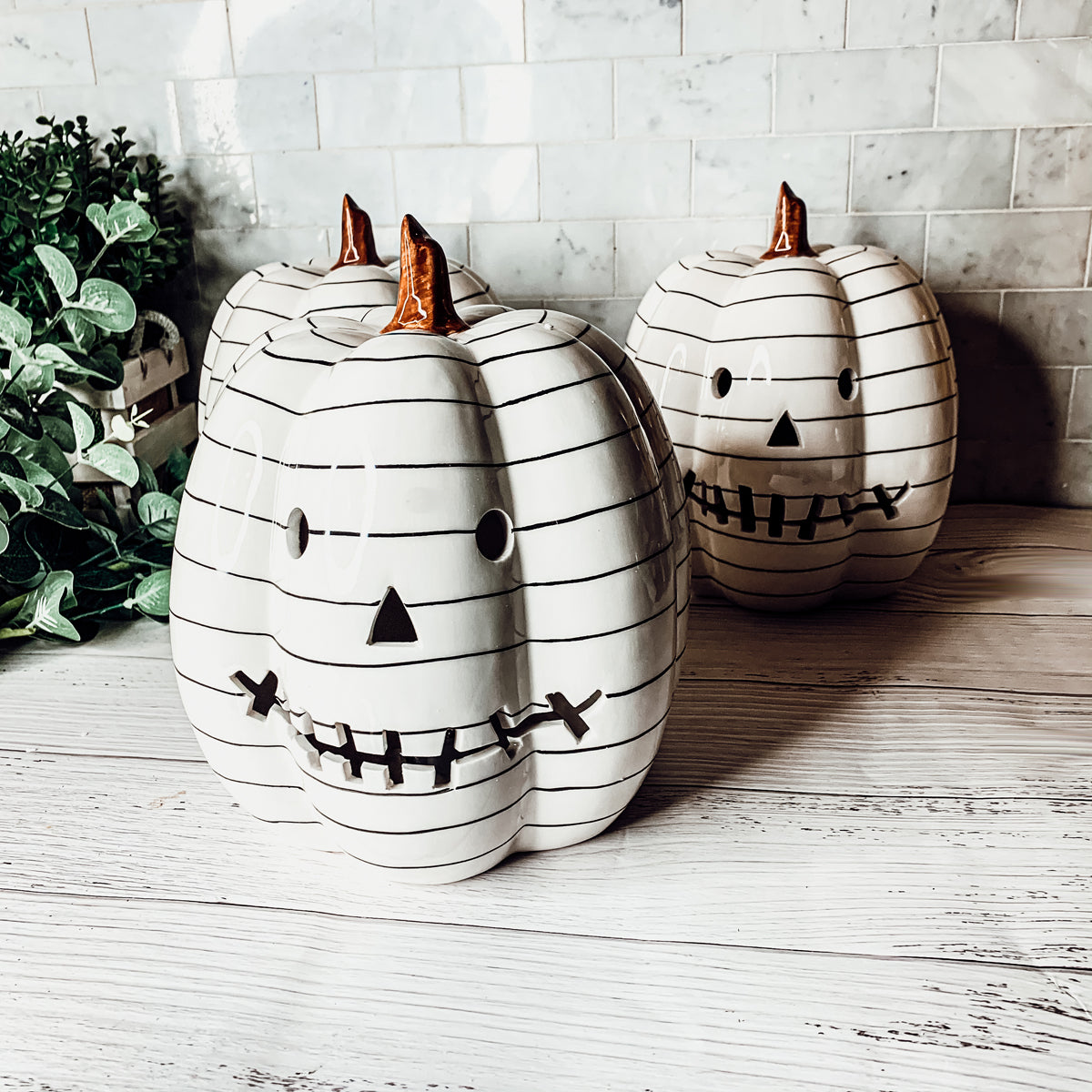 A hand-painted black and white LED pumpkin with a contemporary striped design, perfect for Halloween decor.