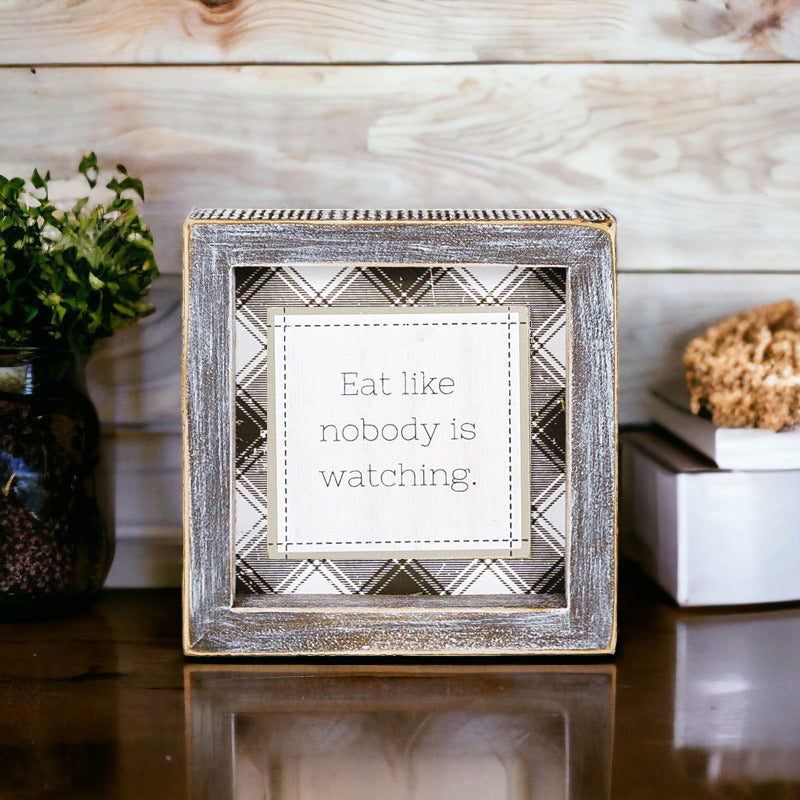 A decorative sign that reads 'Eat Like Nobody is Watching', measuring 5 inches by 5 inches, designed to hang or stand, perfect for kitchens or dining areas.