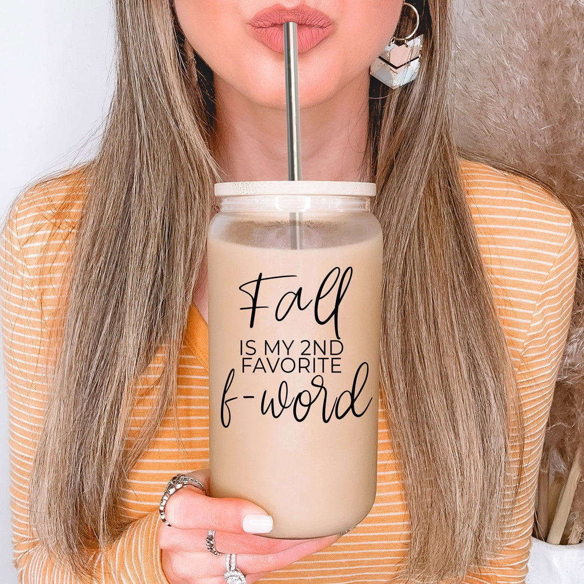 A stylish Fall F-Word Cup made of high borosilicate glass with a bamboo lid, featuring a black graphic text that reads 'FALL IS MY 2ND FAVORITE F-WORD', accompanied by stainless steel straws.