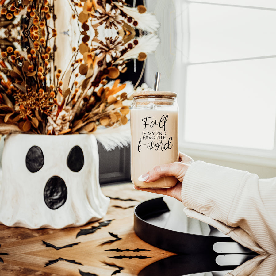 A stylish Fall F-Word Cup made of high borosilicate glass with a bamboo lid, featuring a black graphic text that reads 'FALL IS MY 2ND FAVORITE F-WORD', accompanied by stainless steel straws.