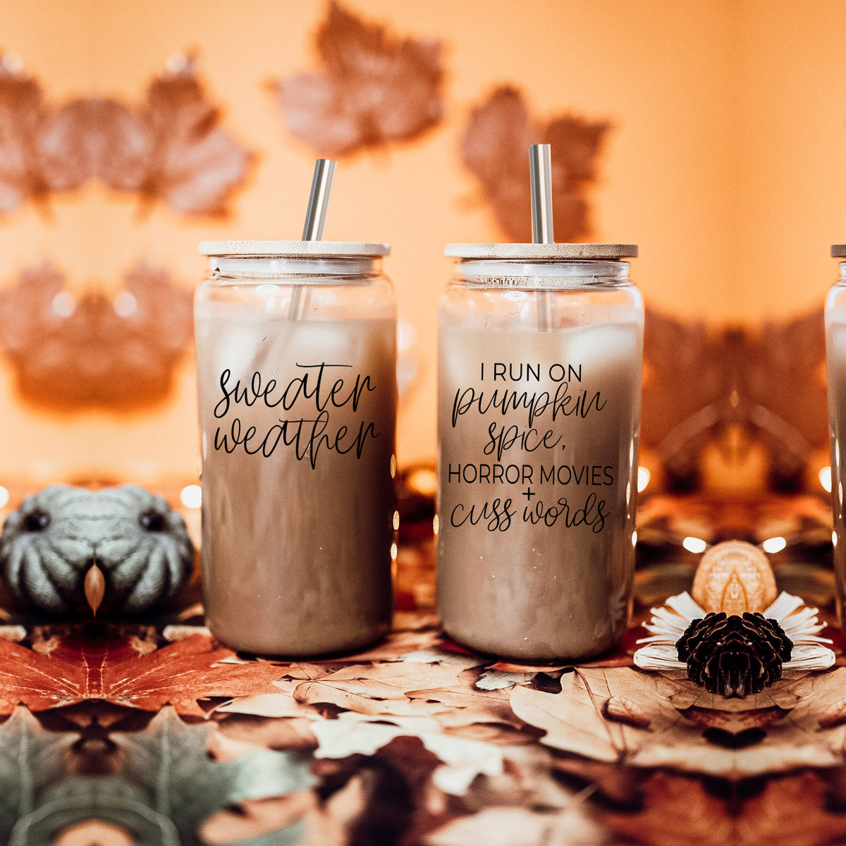 A stylish glass cup with a bamboo lid, featuring the phrase 'I RUN ON PUMPKIN SPICE, HORROR MOVIES + CUSS WORDS' in black graphic design.