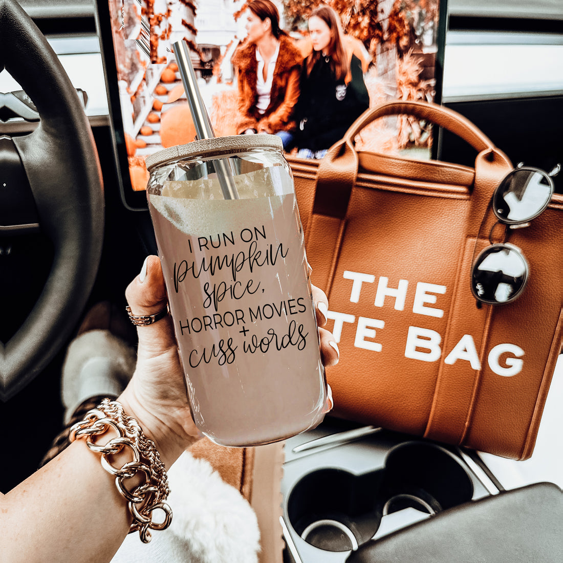 A stylish glass cup with a bamboo lid, featuring the phrase 'I RUN ON PUMPKIN SPICE, HORROR MOVIES + CUSS WORDS' in black graphic design.