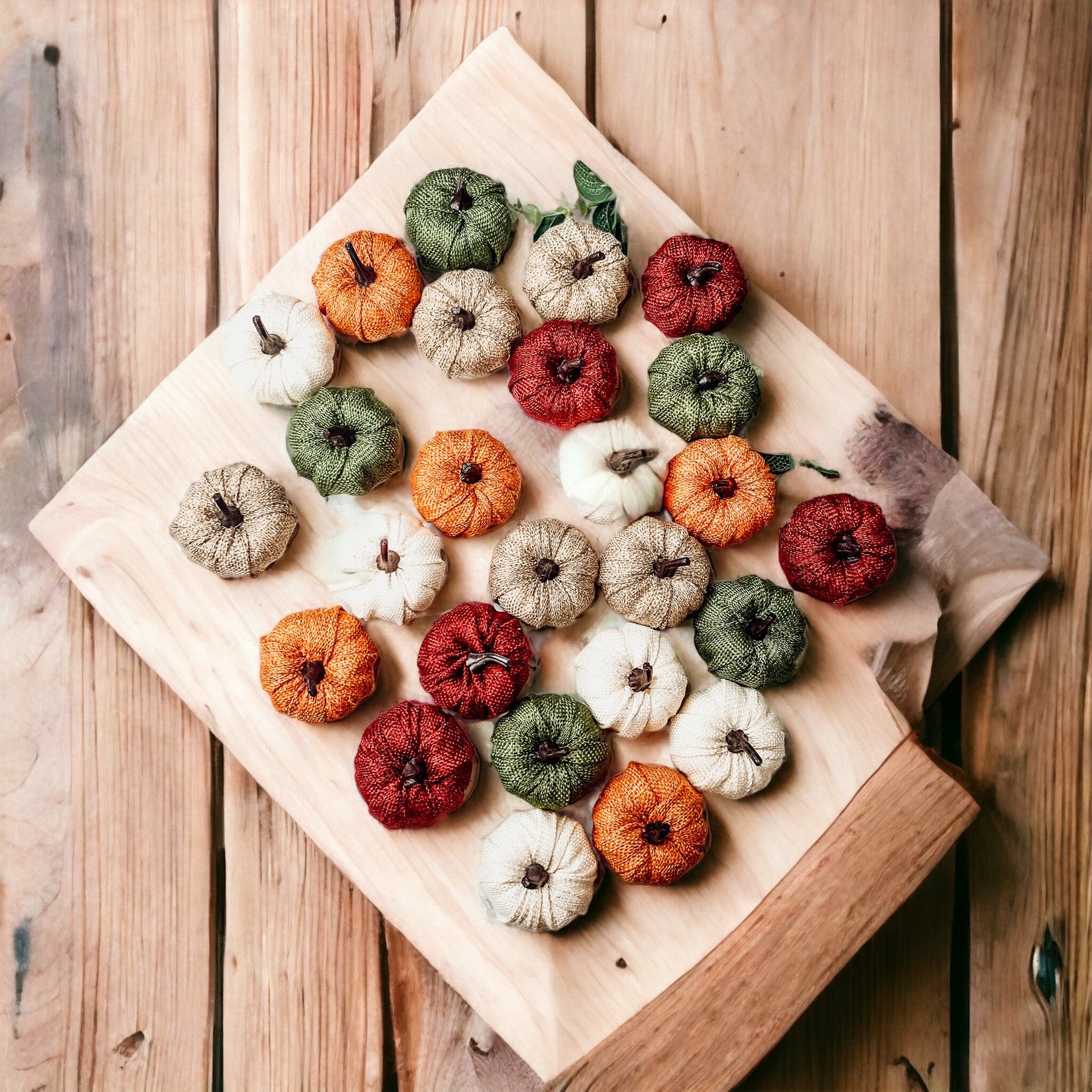 A collection of colorful jute mini pumpkins in various shades including burgundy, beige, green, ivory, and orange, perfect for fall decor.