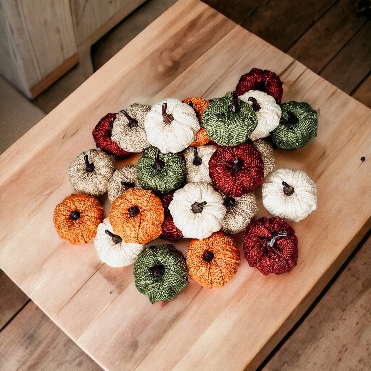 A collection of colorful jute mini pumpkins in various shades including burgundy, beige, green, ivory, and orange, perfect for fall decor.