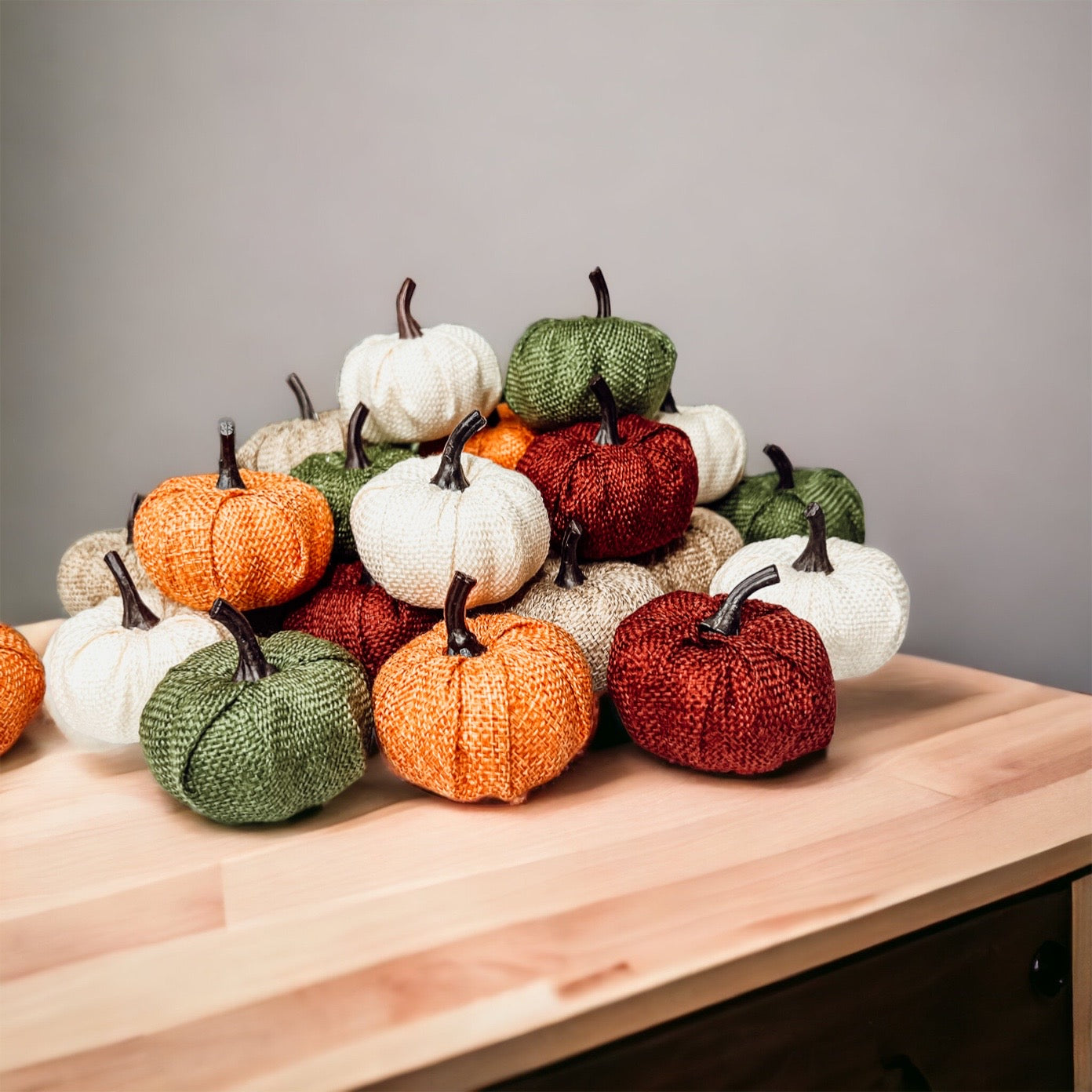 A collection of colorful jute mini pumpkins in various shades including burgundy, beige, green, ivory, and orange, perfect for fall decor.