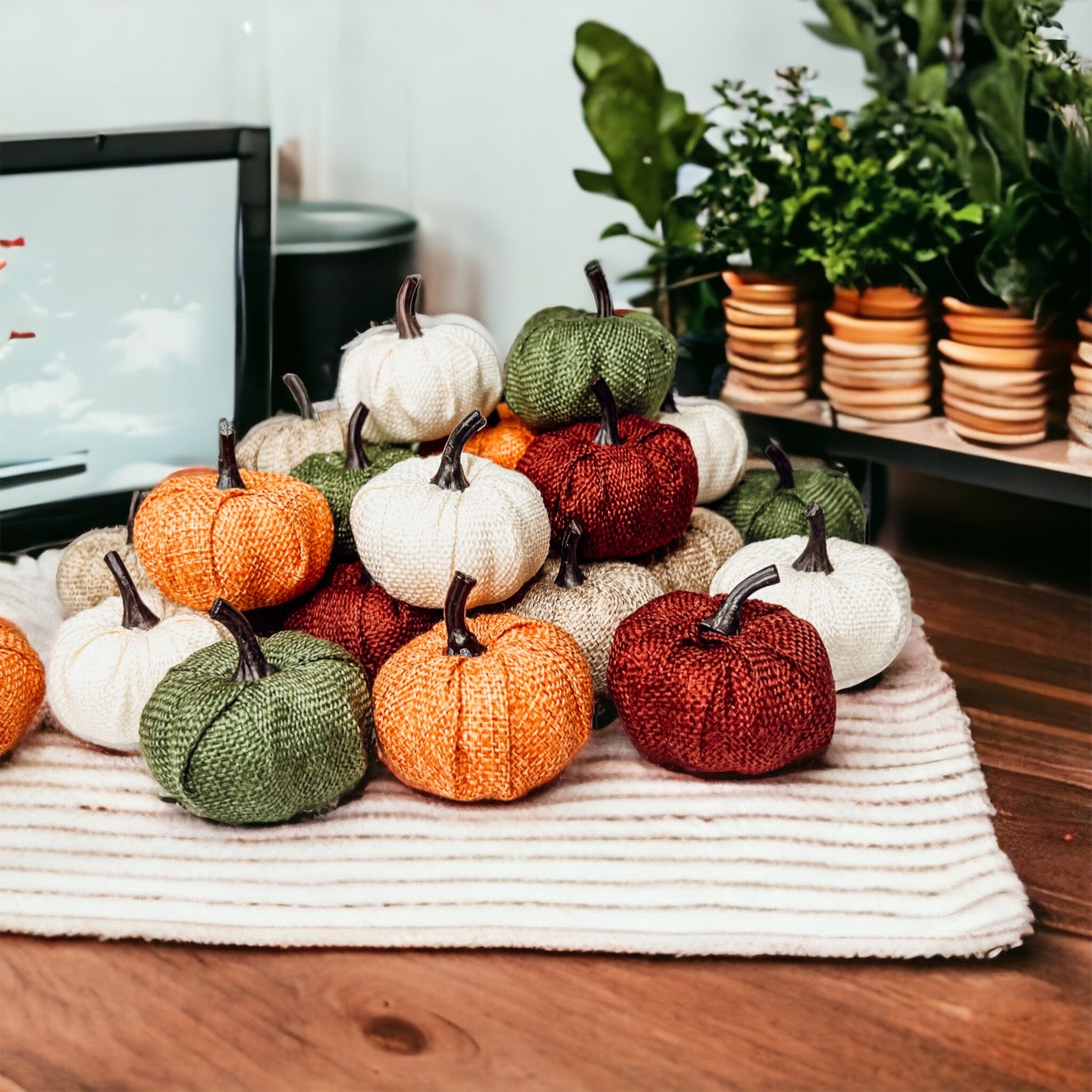 A collection of colorful jute mini pumpkins in various shades including burgundy, beige, green, ivory, and orange, perfect for fall decor.