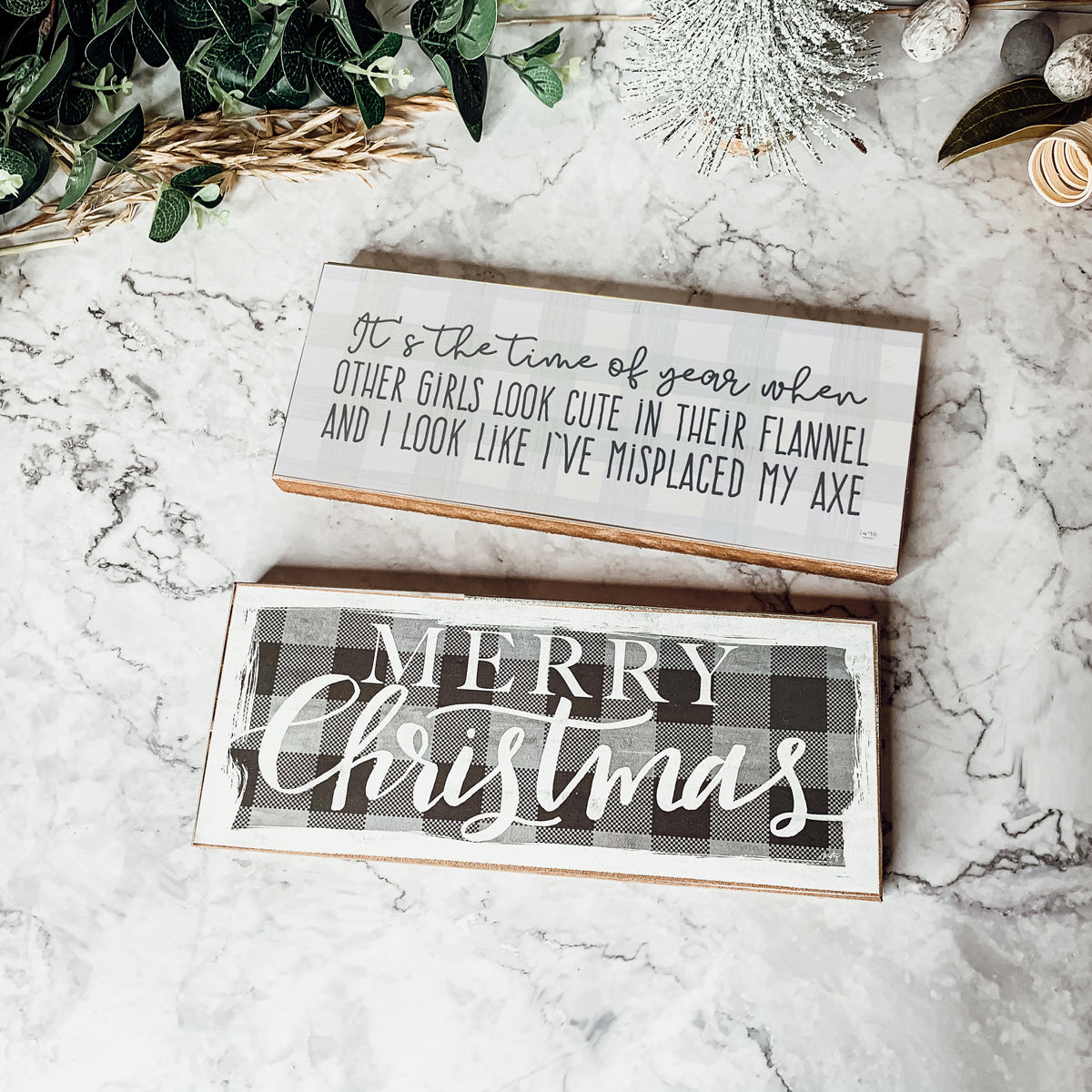 A humorous wooden sign with a flannel design reading 'It's the time of year when other girls look cute in their flannel and I look like I've misplaced my axe.'