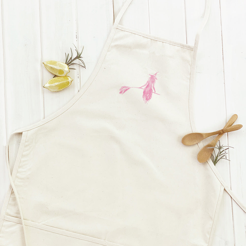 A stylish women's apron featuring a pink witch silhouette design, made from durable cotton canvas with adjustable neck and twill ties.