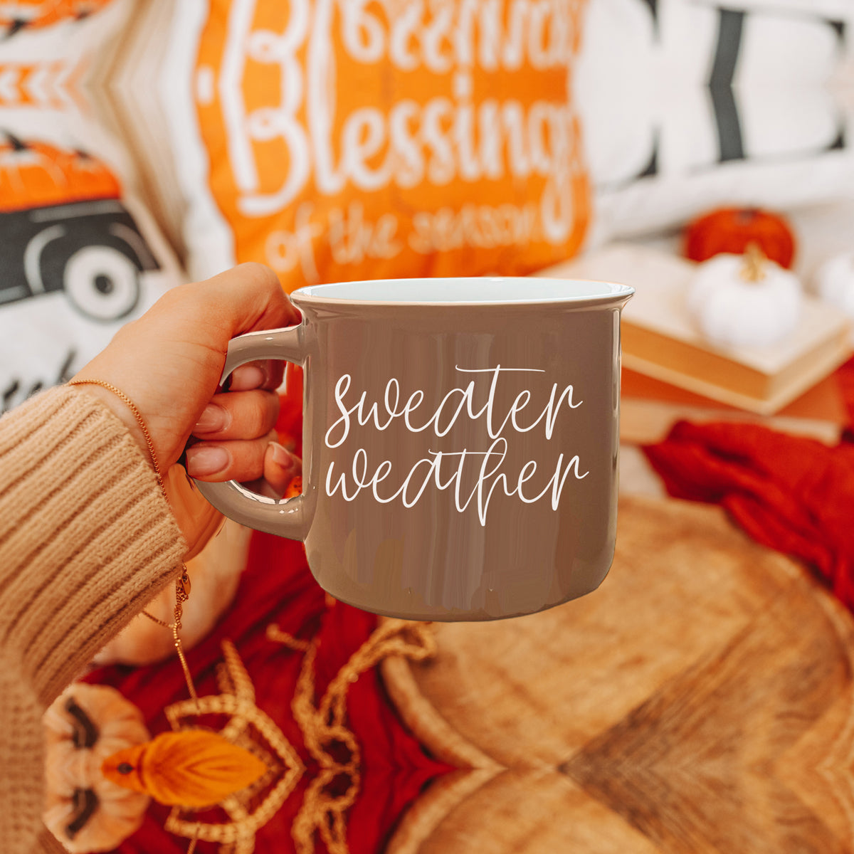 A cozy ceramic campfire style mug in neutral brown with white lettering that says 'Sweater Weather' on both sides.