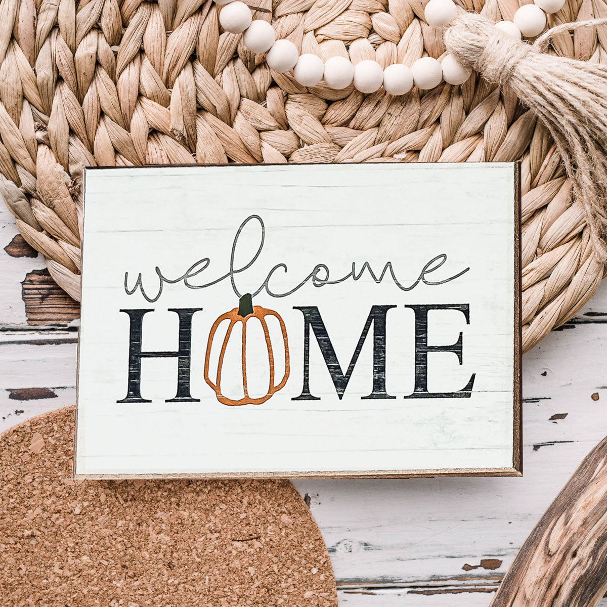 A handmade wooden sign reading 'Welcome Home' with a pumpkin graphic as the 'O', perfect for fall and Halloween decor.