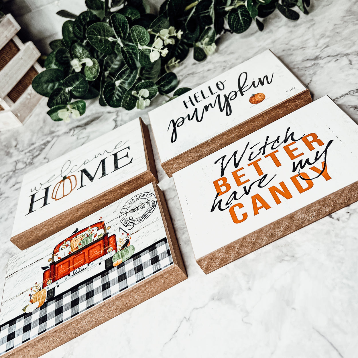 A handmade wooden sign reading 'Welcome Home' with a pumpkin graphic as the 'O', perfect for fall and Halloween decor.