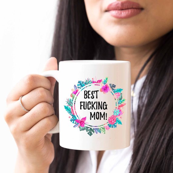 A white ceramic mug with the phrase 'Best Fucking Mom' printed in vibrant colors on both sides, showcasing its high-quality design.