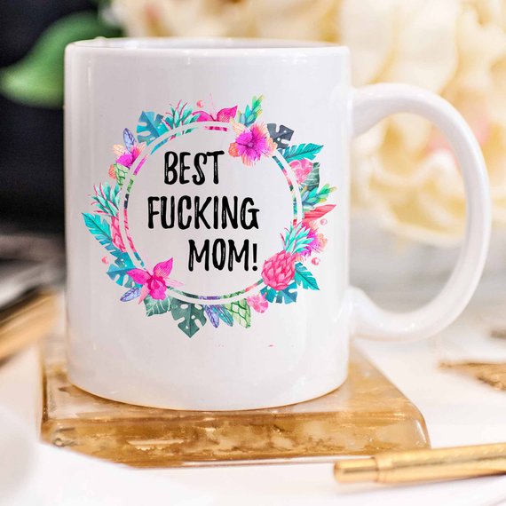 A white ceramic mug with the phrase 'Best Fucking Mom' printed in vibrant colors on both sides, showcasing its high-quality design.