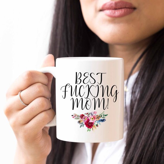 A white ceramic mug with the phrase 'Best Fucking Mom' printed in vibrant colors on both sides, showcasing a humorous and heartfelt design.