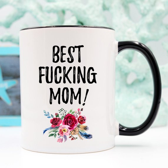 A white ceramic mug with 'Best Fucking Mom' printed in vibrant colors on both sides, showcasing a humorous and heartfelt design.