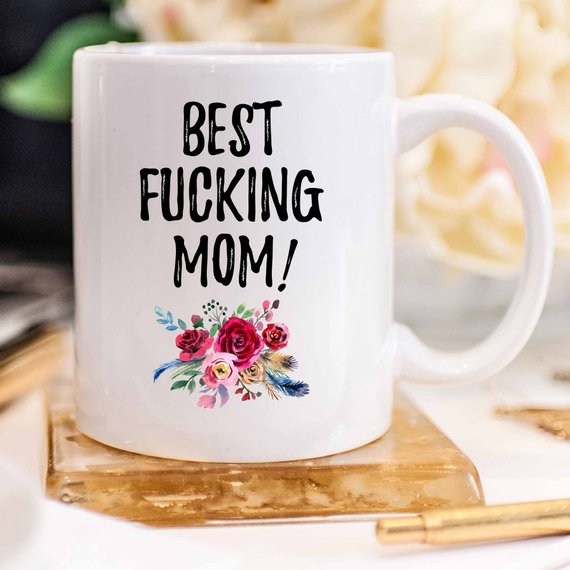 A white ceramic mug with 'Best Fucking Mom' printed in vibrant colors on both sides, showcasing a humorous and heartfelt design.