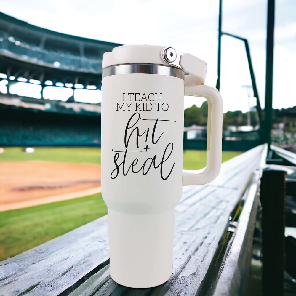 Hit & Steal tumbler with cream exterior and stainless steel interior, featuring a humorous design for baseball moms, double handles, and a no-spill sipping spout.