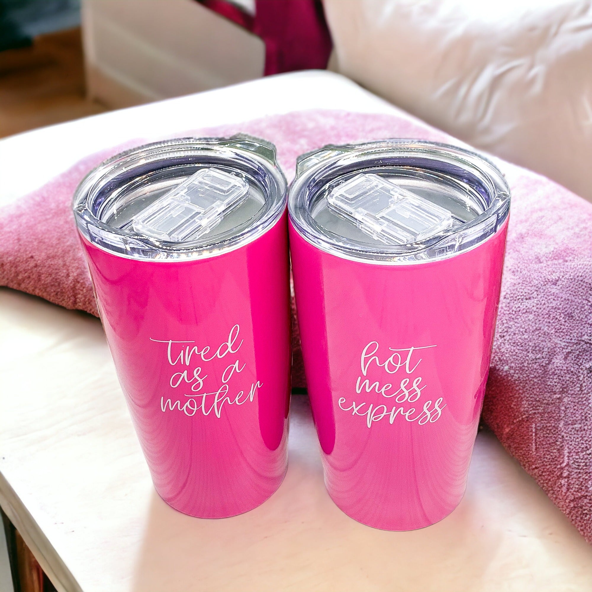 Pink travel mugs with humorous phrases.