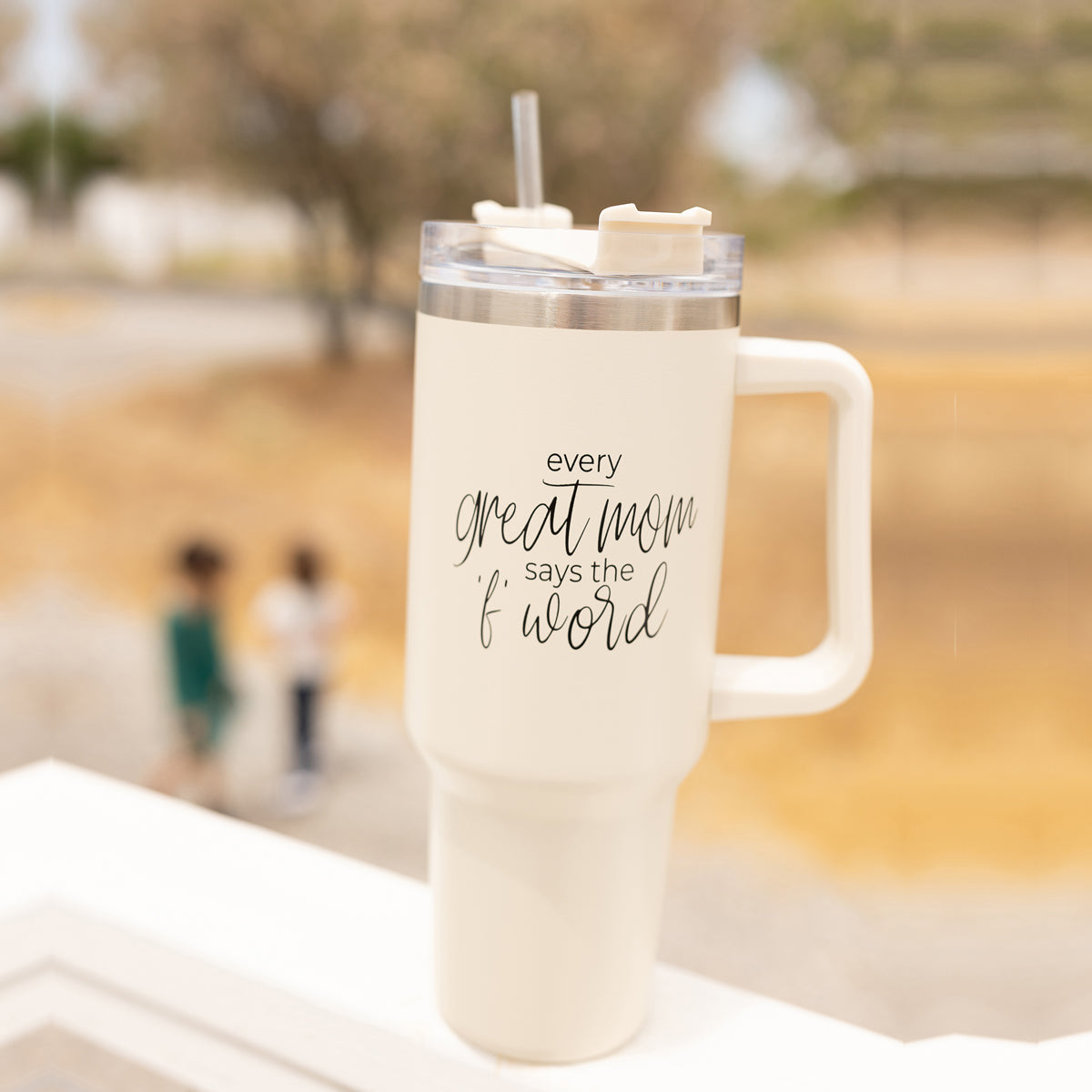 Mom Says the F Word 40oz insulated mug with a matte cream finish, featuring a black graphic design, a removable 3-in-1 lid, and a plastic straw.