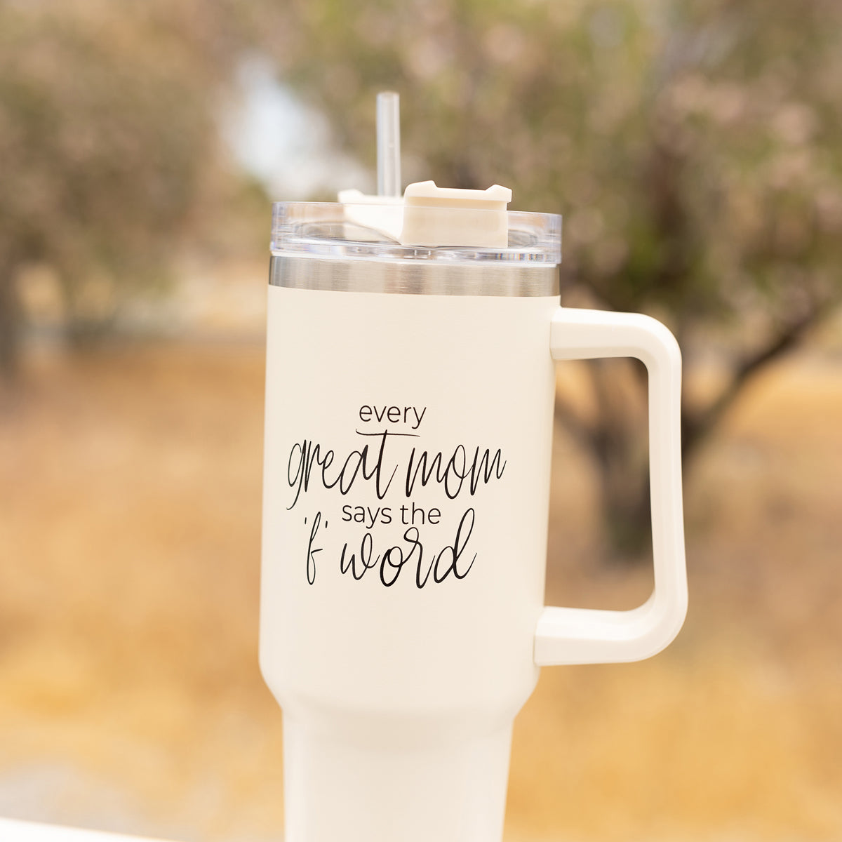 Mom Says the F Word 40oz insulated mug with a matte cream finish, featuring a black graphic design, a removable 3-in-1 lid, and a plastic straw.