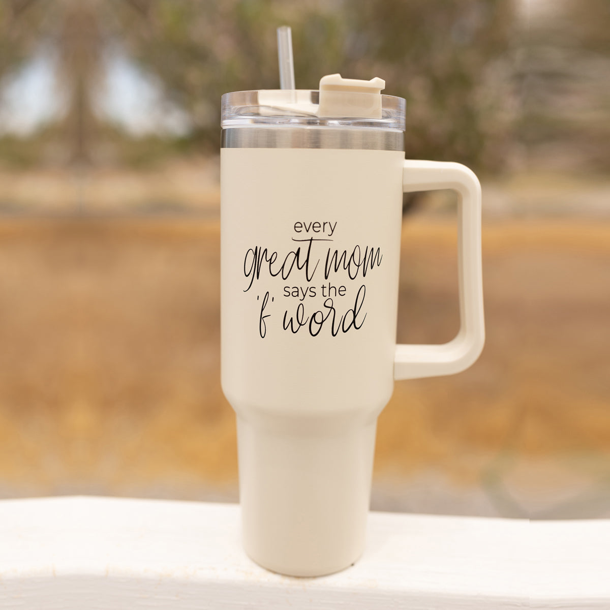 Mom Says the F Word 40oz insulated mug with a matte cream finish, featuring a black graphic design, a removable 3-in-1 lid, and a plastic straw.