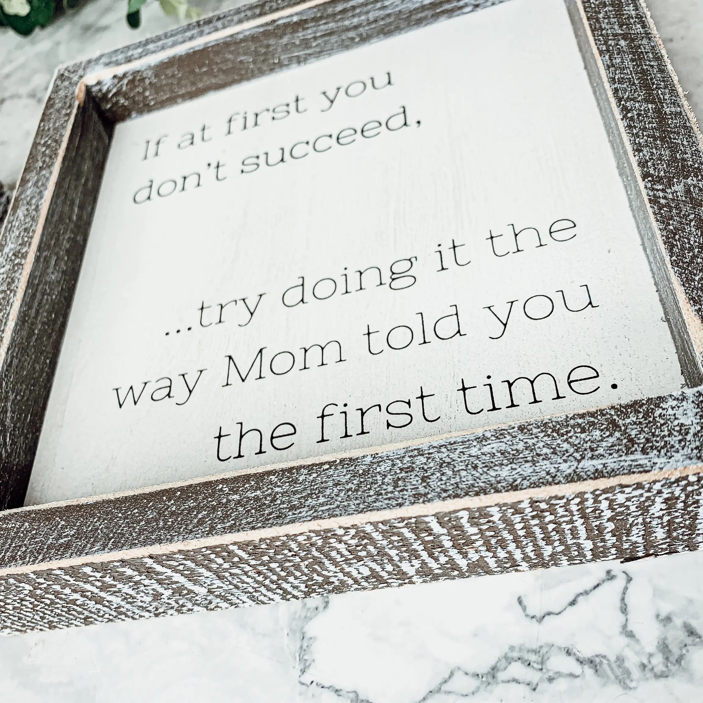 A wooden sign framed in wood, measuring 7x7 inches, featuring a humorous quote about motherhood, suitable for wall hanging or standing display.