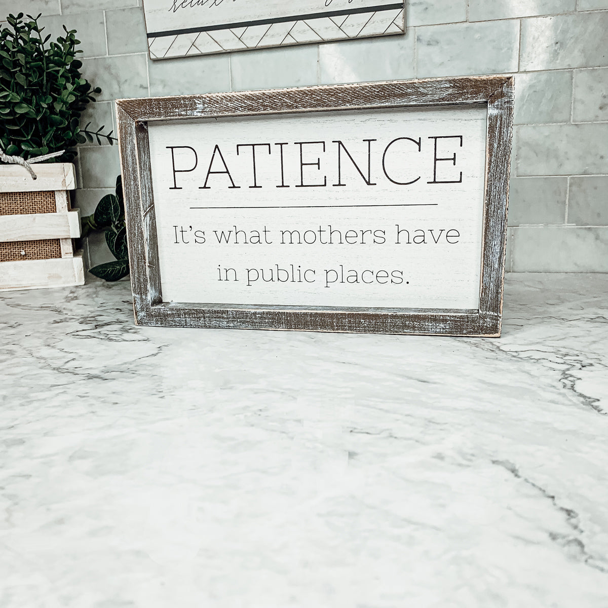 Wooden framed sign with the phrase 'Patience, It's What Mothers Have In Public Places', measuring 10" x 6" x 1.5", suitable for hanging or freestanding display.