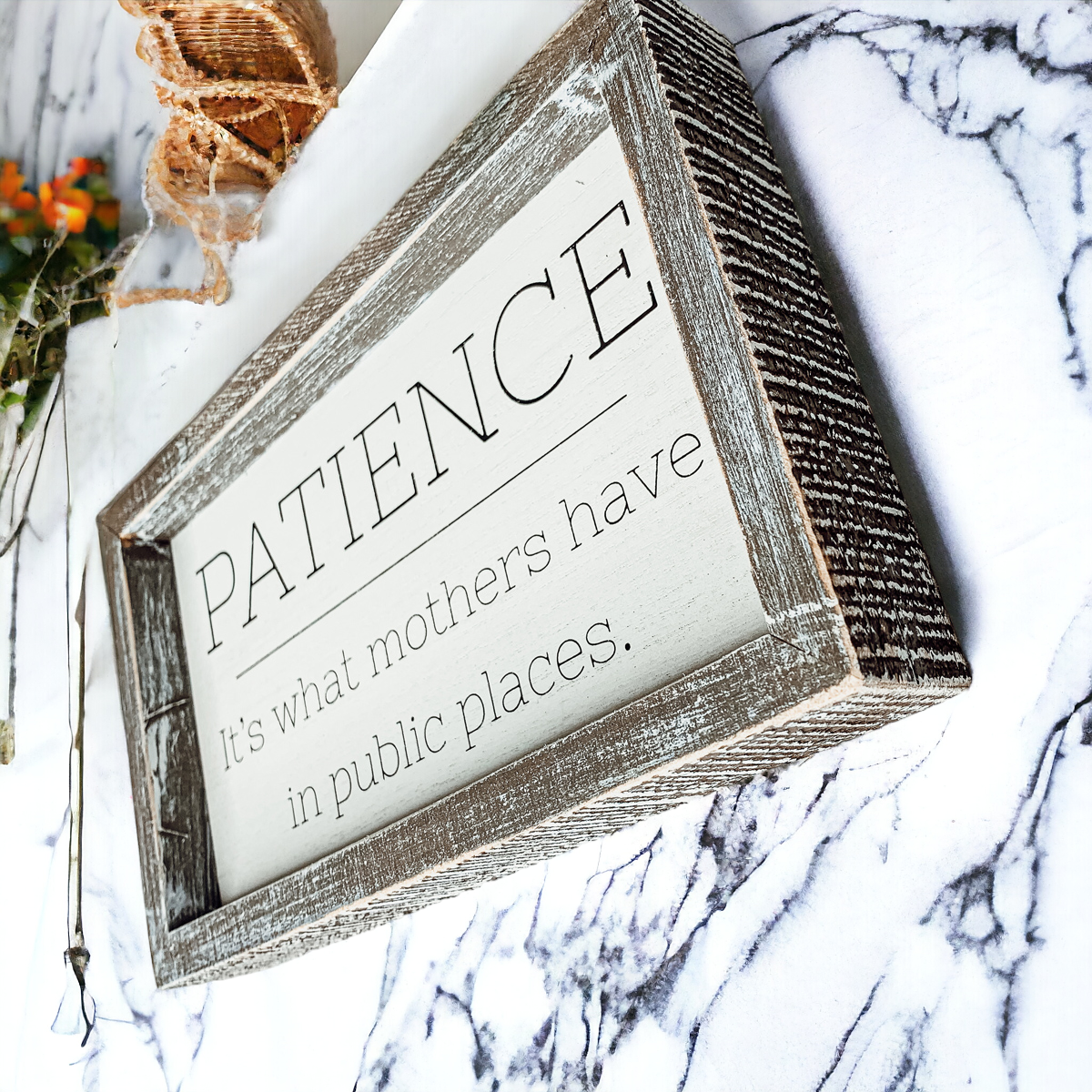 Wooden framed sign with the phrase 'Patience, It's What Mothers Have In Public Places', measuring 10" x 6" x 1.5", suitable for hanging or freestanding display.