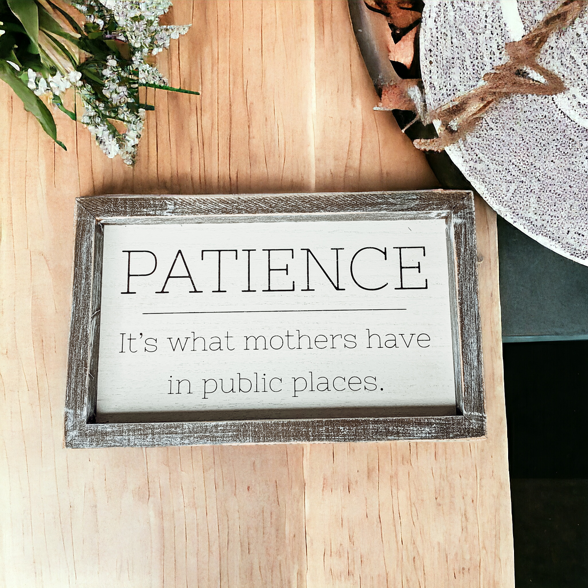 Wooden framed sign with the phrase 'Patience, It's What Mothers Have In Public Places', measuring 10" x 6" x 1.5", suitable for hanging or freestanding display.