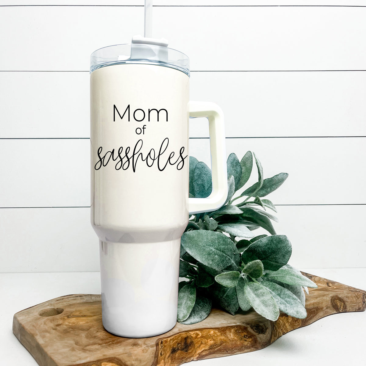 Mom of Sassholes 40oz insulated mug with handle, lid, and straw, featuring a cream exterior and black graphic design.