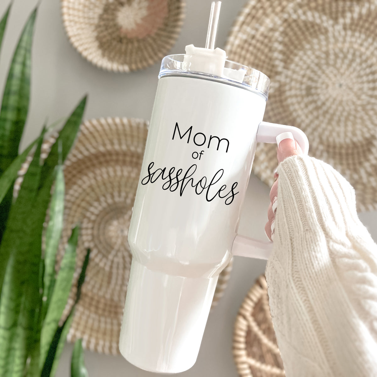 Mom of Sassholes 40oz insulated mug with handle, lid, and straw, featuring a cream exterior and black graphic design.