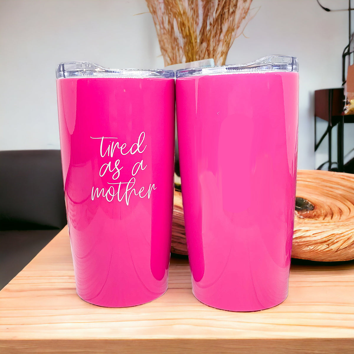 A stylish pink stainless steel travel mug with the phrase 'Tired as a Mother' printed on it, featuring a push-on lid and a non-skid foam bottom.