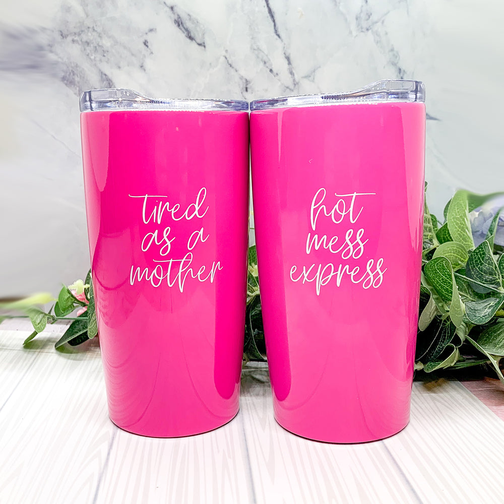 A stylish pink stainless steel travel mug with the phrase 'Tired as a Mother' printed on it, featuring a push-on lid and a non-skid foam bottom.