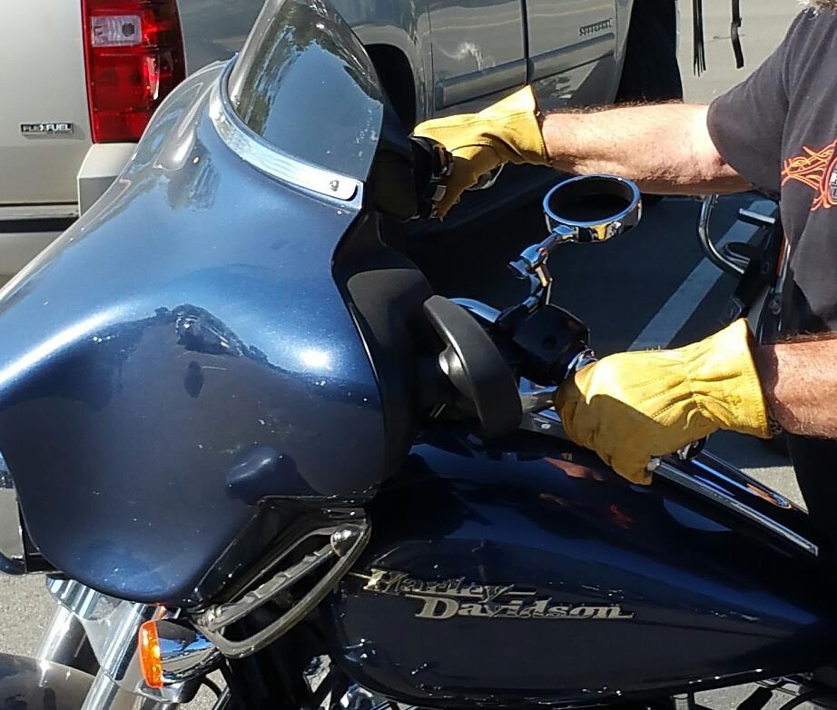 Person holding a Harley-Davidson motorcycle.