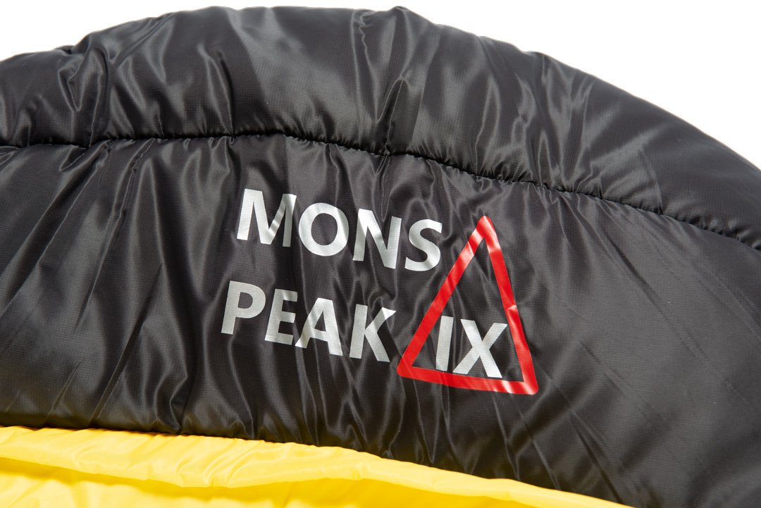 Settler 15 F sleeping bag displayed outdoors, showcasing its dual zippers, soft nylon fabric, and hood with cinch draw cords.