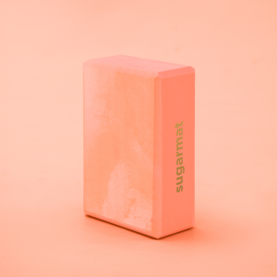 A pink yoga block made of high-density EVA foam, featuring beveled edges for grip, ideal for supporting various yoga poses.