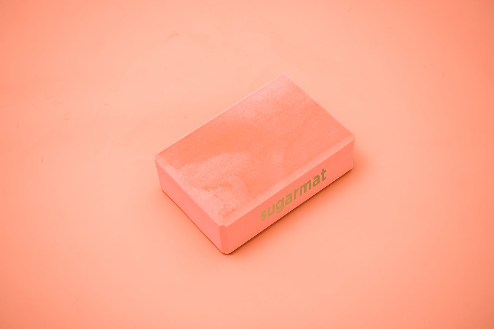 A pink yoga block made of high-density EVA foam, featuring beveled edges for grip, ideal for supporting various yoga poses.