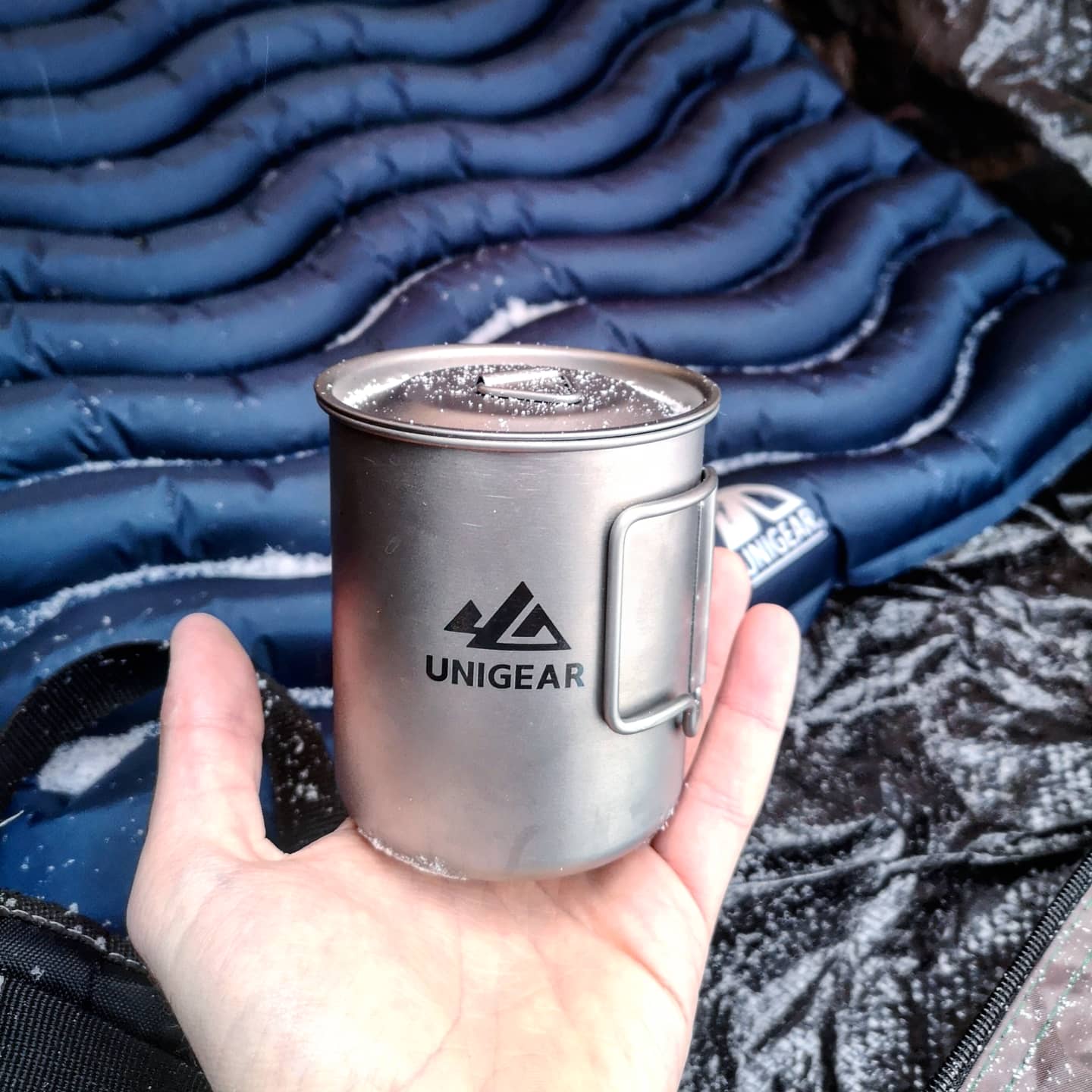 A 100% titanium camping cup with folding handles, showcasing its lightweight and durable design, perfect for outdoor adventures.