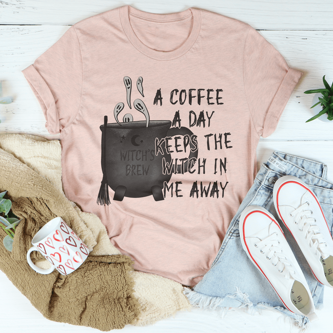 A stylish black t-shirt with the phrase 'A Coffee A Day Keeps The Witch In Me Away' printed in white, showcasing its soft fabric and durable stitching.