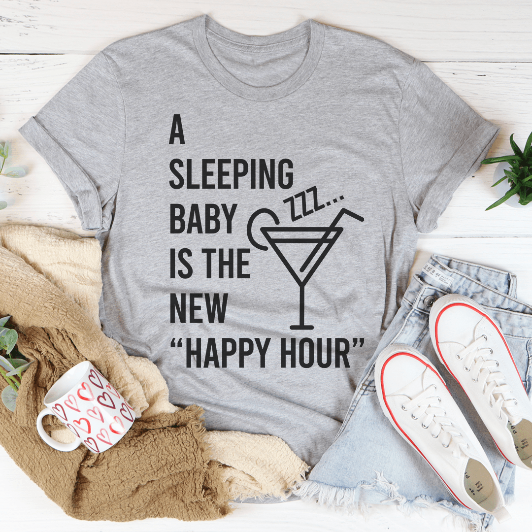 A soft and durable A Sleeping Baby Is The New Happy Hour Tee displayed on a hanger, showcasing its stylish design and quality fabric.