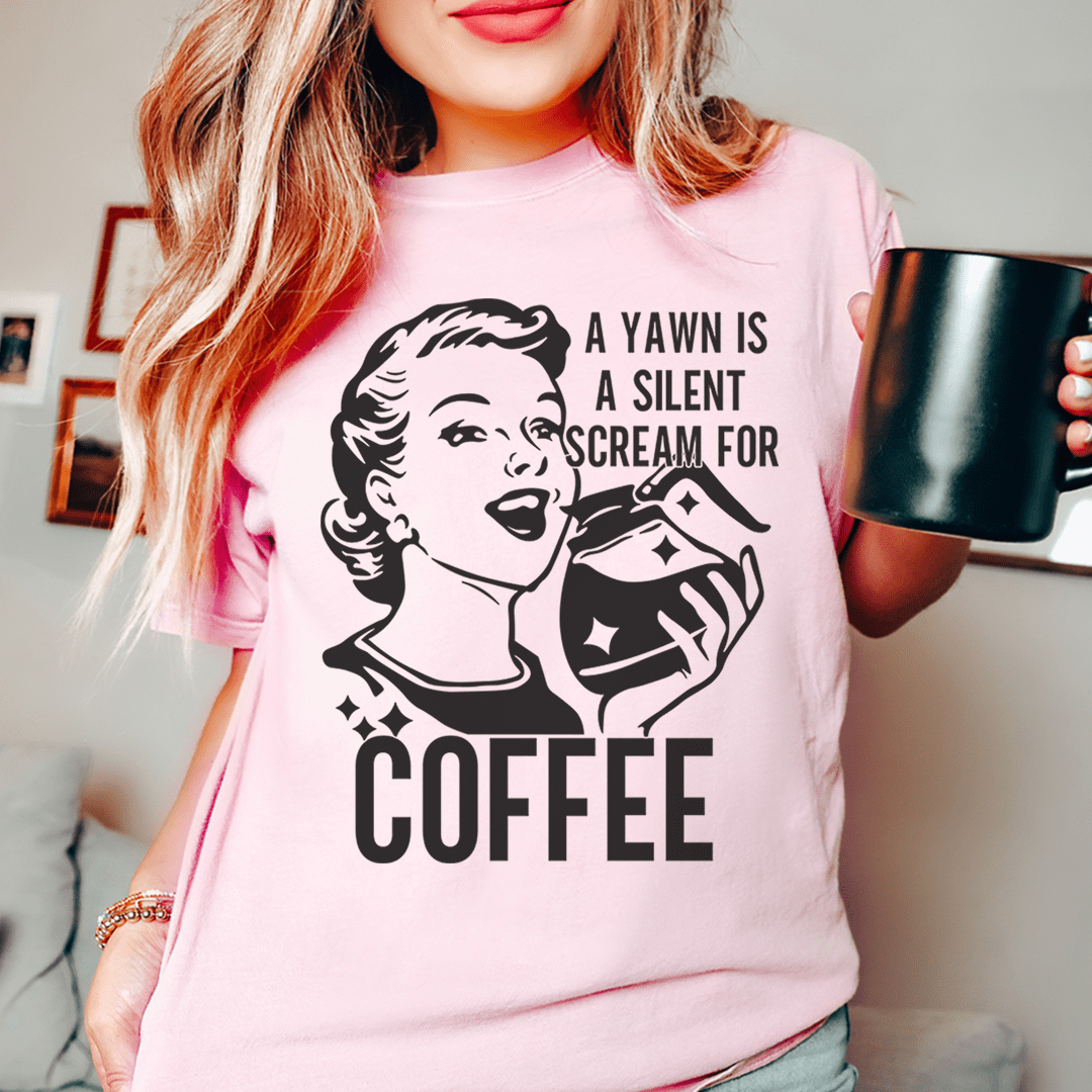 A comfortable and stylish t-shirt featuring the phrase 'A Yawn Is A Silent Scream For Coffee' printed on it, made from soft ring-spun cotton.