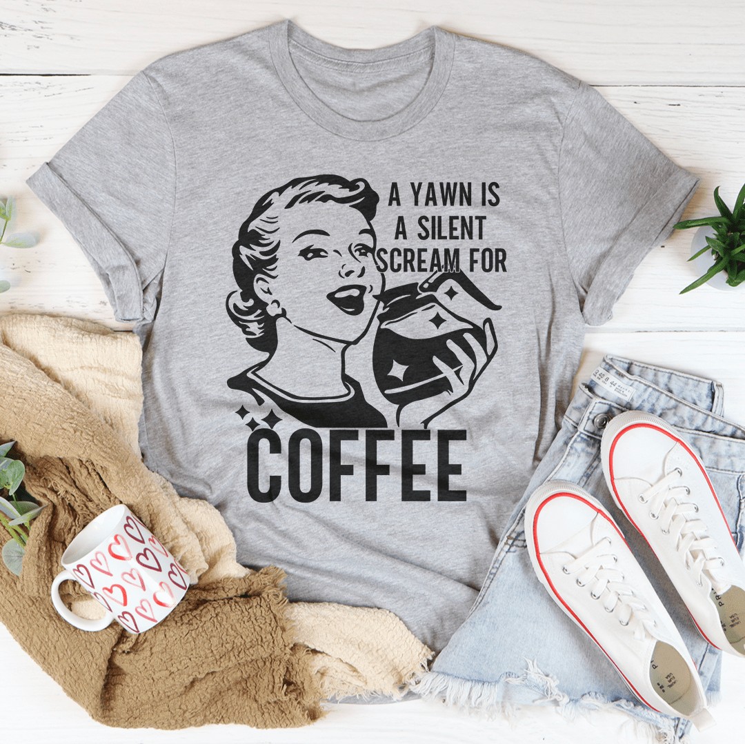 A comfortable and stylish t-shirt featuring the phrase 'A Yawn Is A Silent Scream For Coffee' printed on it, made from soft ring-spun cotton.