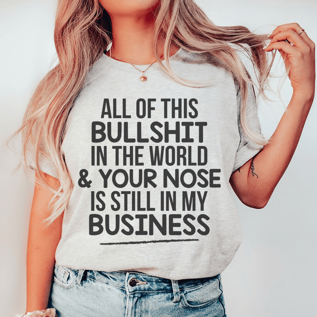 A stylish t-shirt featuring the phrase 'All Of This B.S In The World & Your Nose Is Still In My Business' printed on soft, durable cotton fabric.