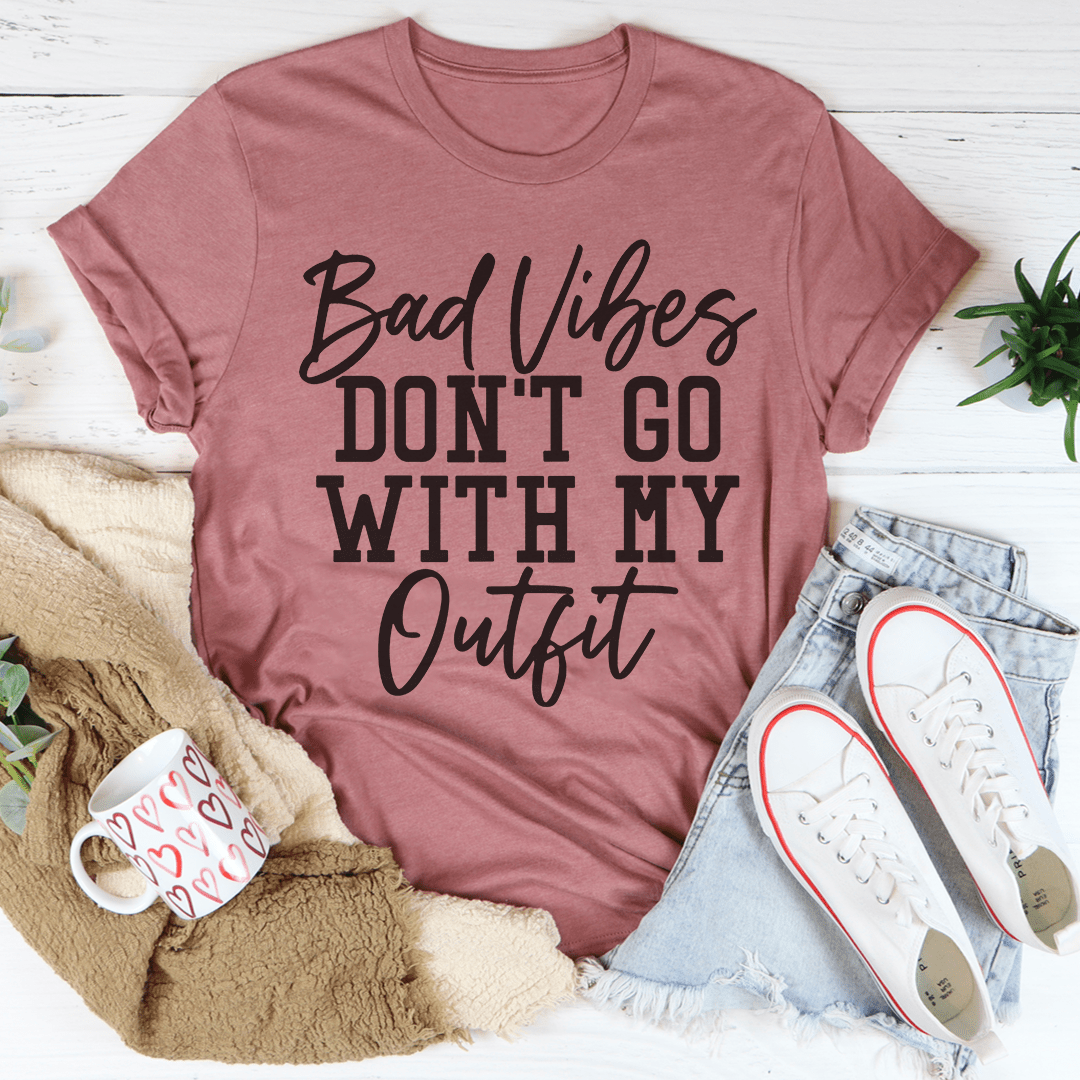 A stylish black t-shirt with the phrase 'Bad Vibes Don't Go With My Outfit' printed in bold letters, showcasing its soft fabric and durable stitching.