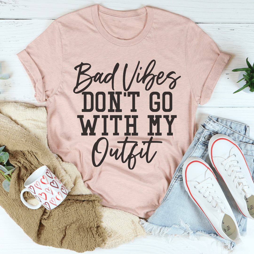 A stylish black t-shirt with the phrase 'Bad Vibes Don't Go With My Outfit' printed in bold letters, showcasing its soft fabric and durable stitching.