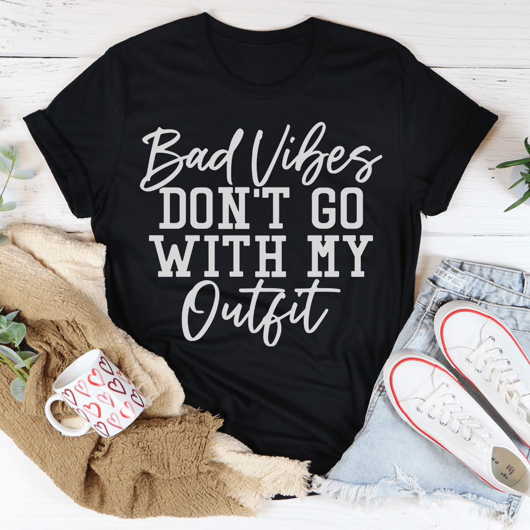 A stylish black t-shirt with the phrase 'Bad Vibes Don't Go With My Outfit' printed in bold letters, showcasing its soft fabric and durable stitching.