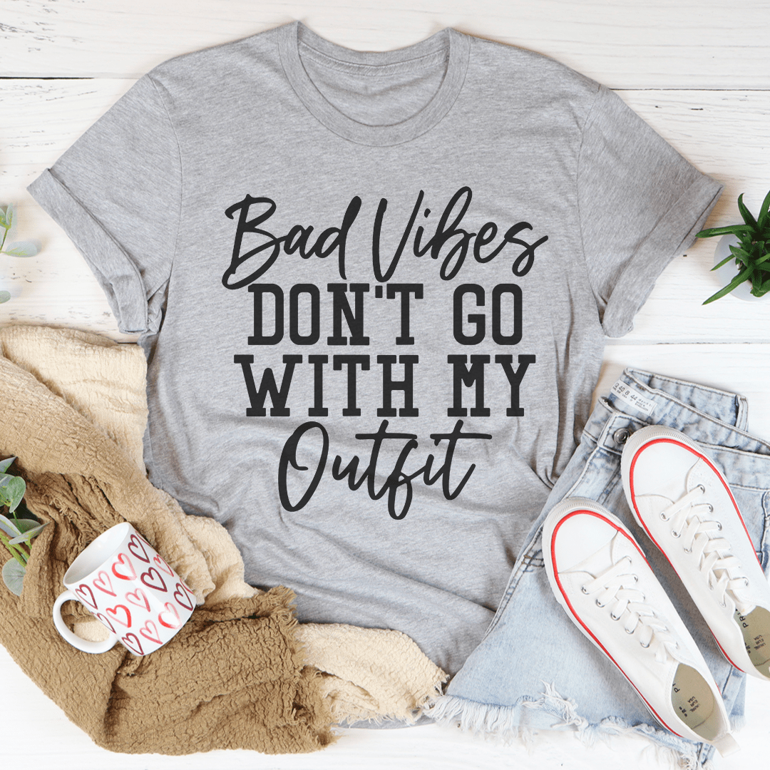 A stylish black t-shirt with the phrase 'Bad Vibes Don't Go With My Outfit' printed in bold letters, showcasing its soft fabric and durable stitching.